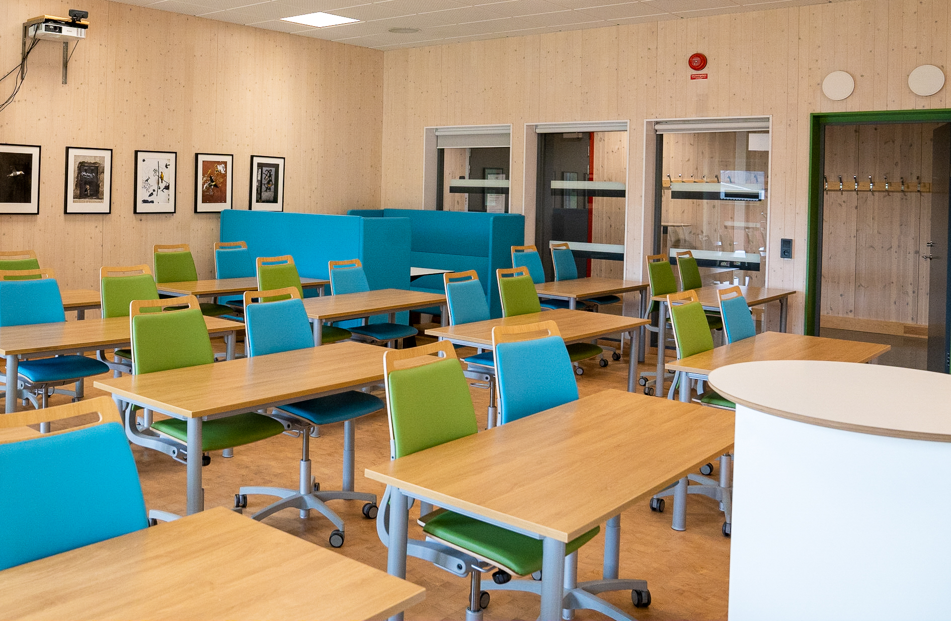 Lektionssal med bord och stolar vända mot undervisningstavla
