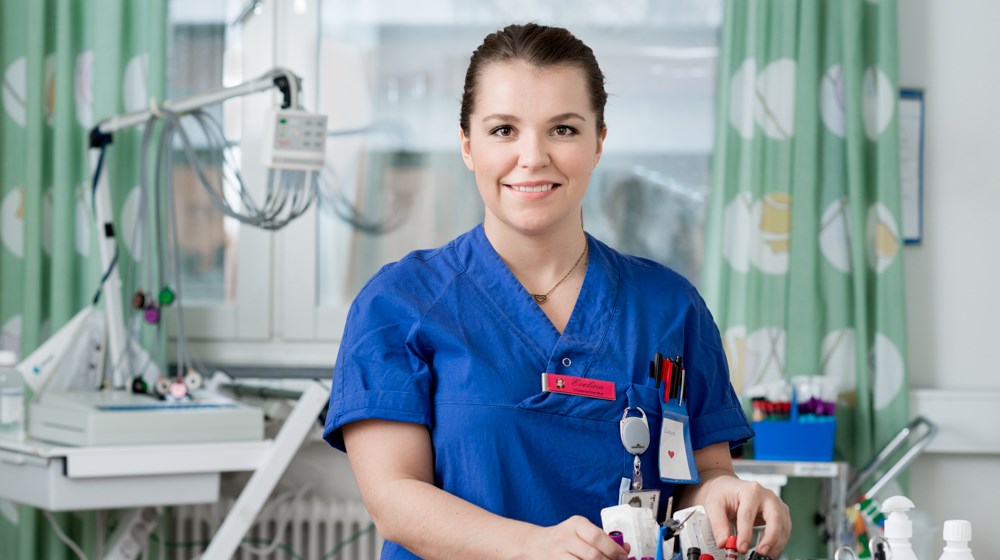 Blåklädd vårdpersonal står  framför ett fönster. 