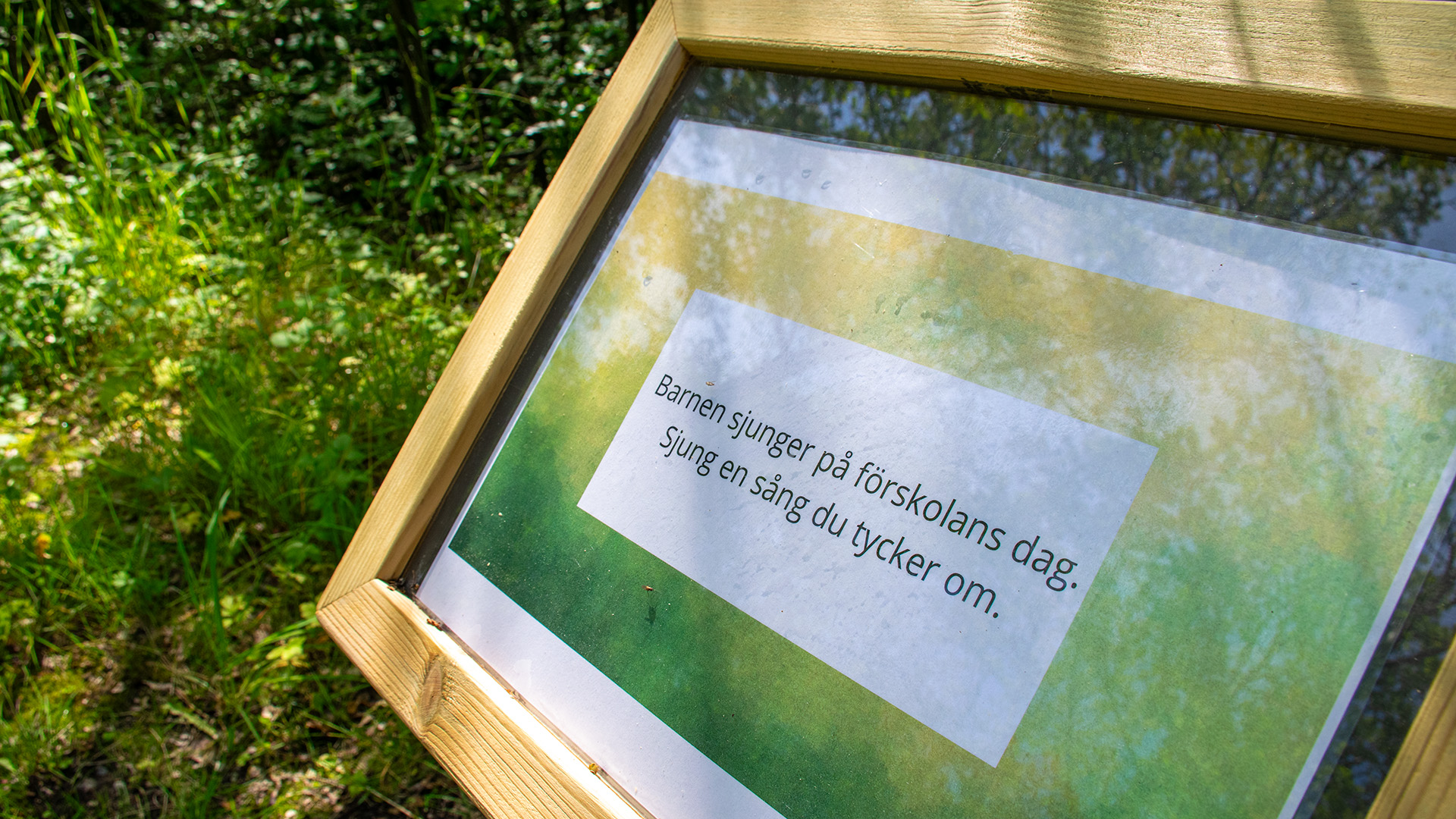 På en skylt står det: "Barnen sjunger på förskolans dag. Sjung en sång du tycker om". 
