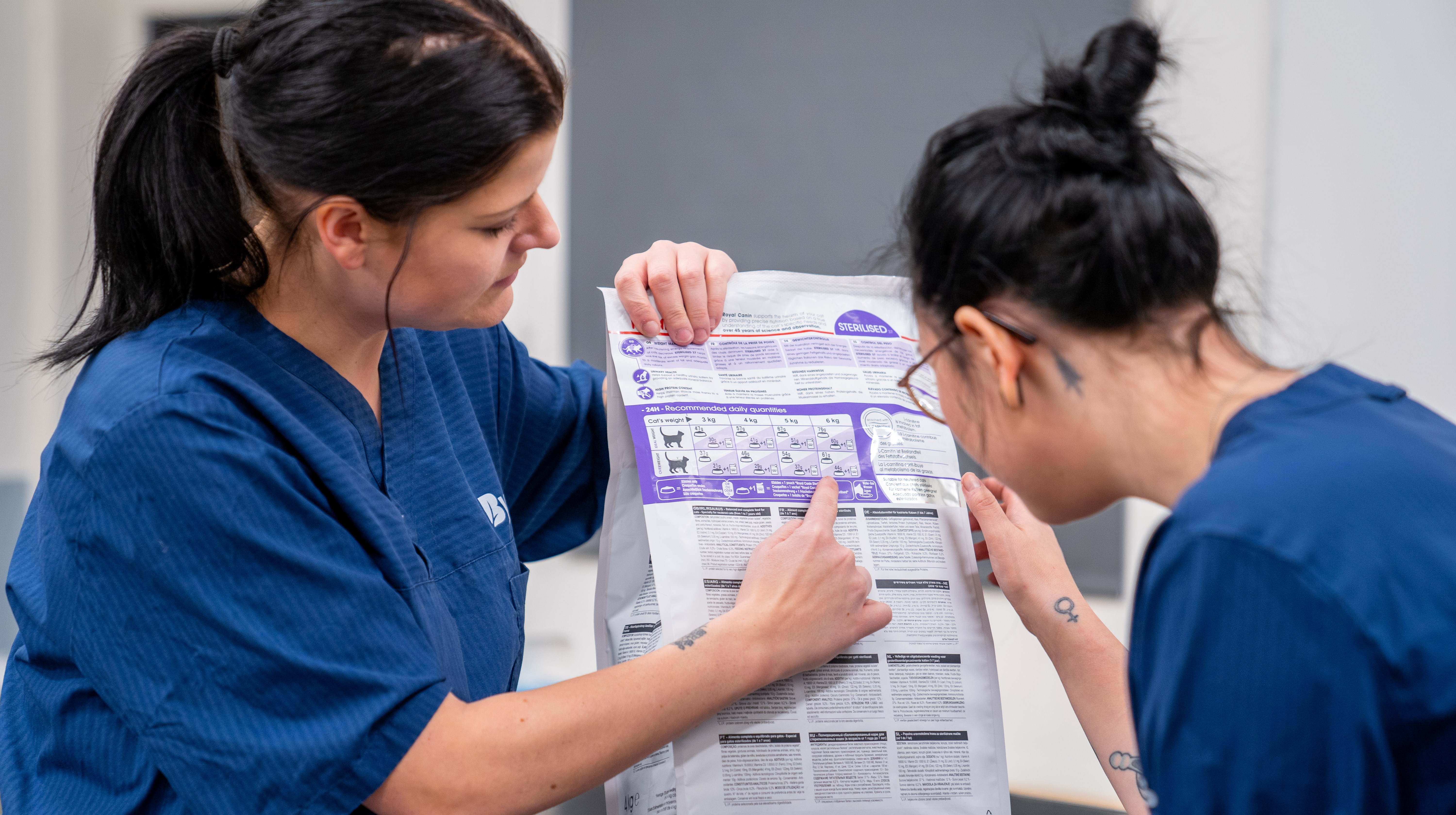 Två djurvårdselever tittar på en foderpåse