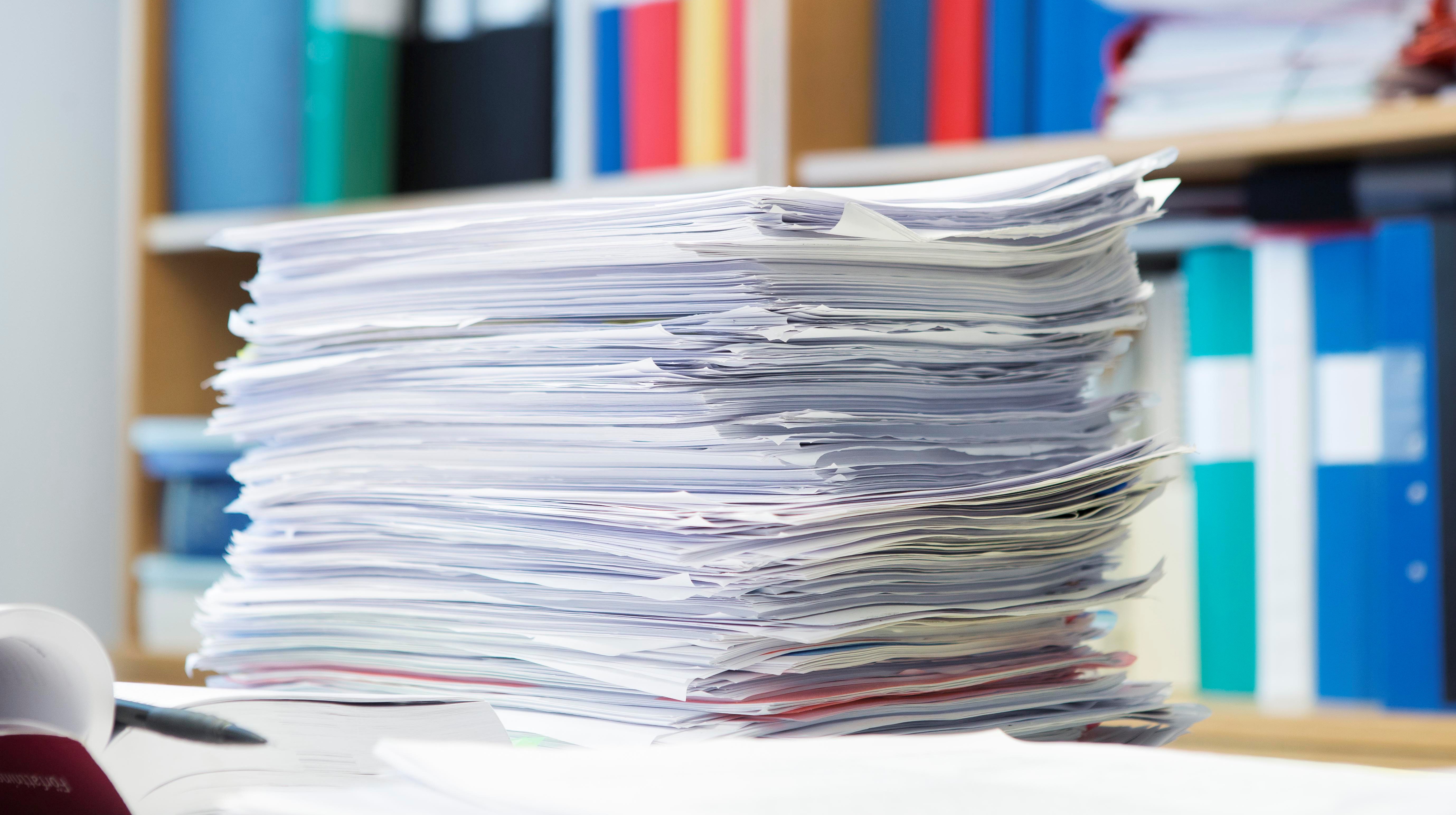bild på en stor hög med papper och dokumentsamlingar i en  kontorsmiljö