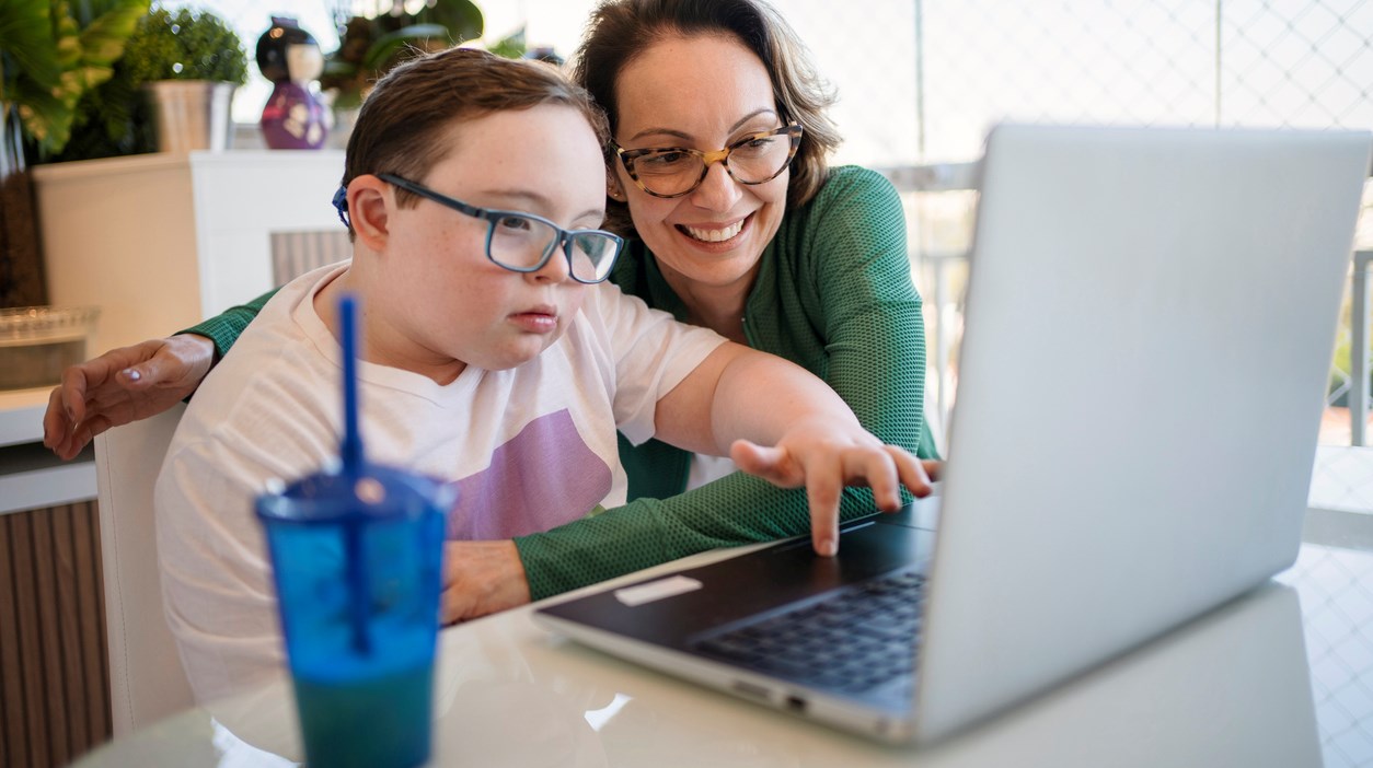 Mother and son using laptop at home for homeschooling.