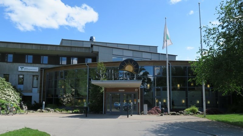 Glasbyggnad med en bild på en sol över entrén