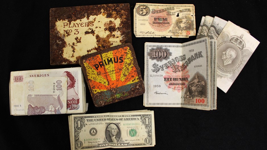 Gamla sedlar och en ask där det står Primus samt en rostig ask där det står Players no 3.